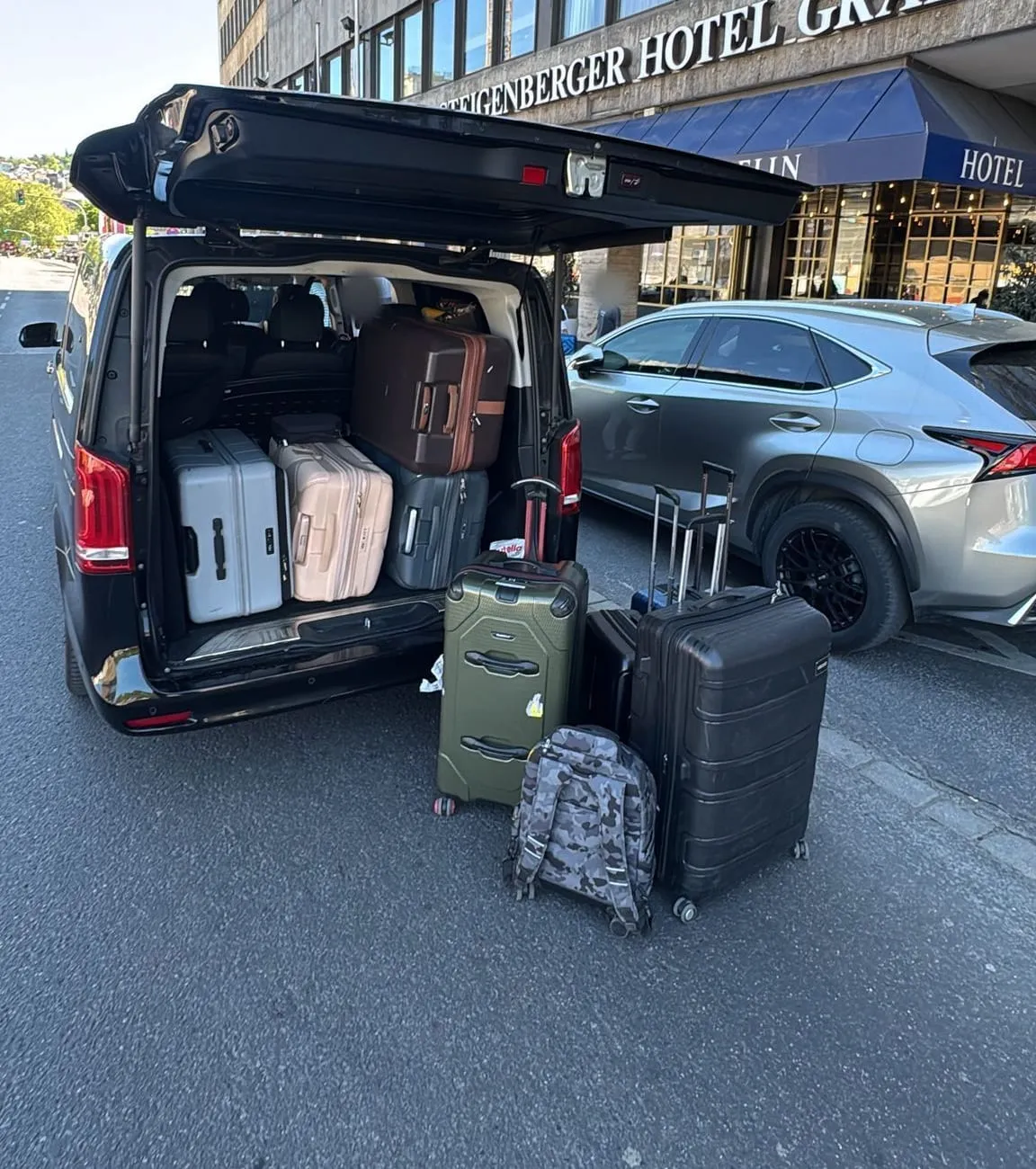 Boot of a Strasbourg Van Mercedes loaded with eight suitcases in front of a hotel